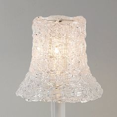 a glass table lamp with a white shade on the top and bottom part of it