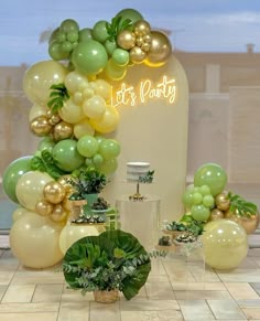 balloons and greenery are on display in front of a party sign