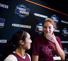 two women are talking to each other in front of a wall with the words march madness on it