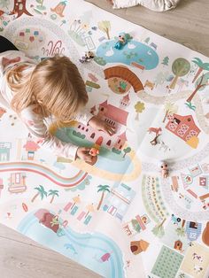 a little boy laying on top of a floor covered in colorful wallpaper and playing with toys