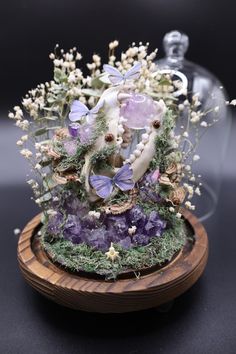 a vase filled with lots of purple and white flowers on top of a wooden stand