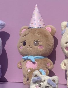 three teddy bears are sitting next to each other with a party hat on their head