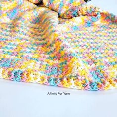 a crocheted blanket is laying on a white surface with a stuffed animal in it