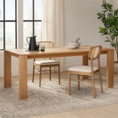 a dining table with two chairs next to a potted plant and vase on the floor