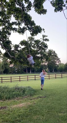 two people in a field playing with a frisbee on a swing set near a fence