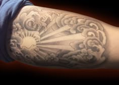 a man's arm with clouds and sun tattoo on it