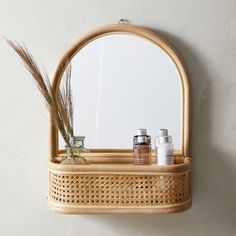 a bamboo shelf with some jars on it and a mirror in the corner next to it