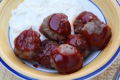 some meatballs are covered in sauce on a plate with white yogurt and blue trim