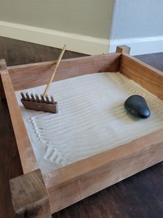 a wooden tray with a rock and brush in it on top of a wood floor