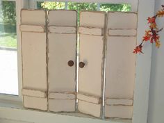 an open window with white shutters in front of it and flowers on the windowsill