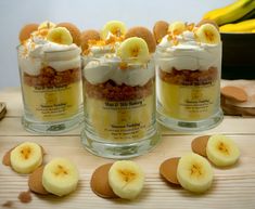 three desserts with banana slices and whipped cream on top are arranged in glass containers