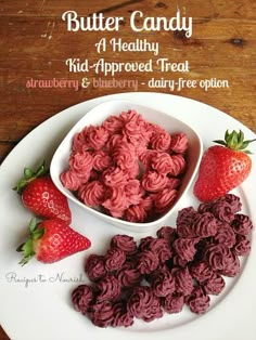 a white plate topped with strawberries next to a bowl of red velvet candy and two strawberries