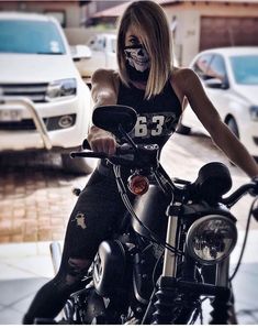 a woman with face paint sitting on a motorcycle