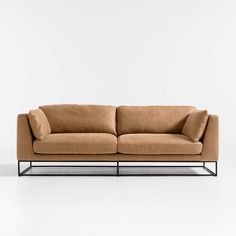 a tan couch sitting on top of a white floor next to a black metal frame