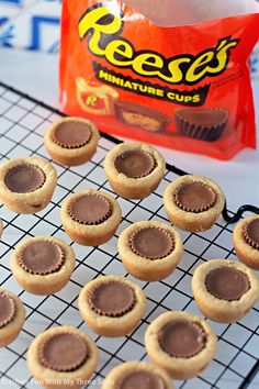 peanut butter cupcakes on a cooling rack next to a bag of reese's