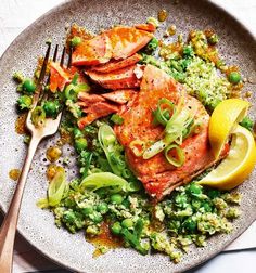 a plate with salmon, broccoli and lemon wedges next to a fork