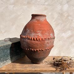 a clay vase sitting on top of a wooden table next to an old box and eyeglasses