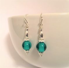 "These stunningly shiny dangle earrings feature a single deep turquoise glass bead with silver tone earrings wires and findings. These beauties hand almost 1 5/8\" from a piercing.  All my jewelry is made with great joy, so should you be unhappy with your choice, please contact me immediately and I will do my very best to remedy the issue. Should you have any questions, please send me a message. And as always, thank you for your interest." Bead Dangles, Deep Turquoise, Teal Earrings, Earrings Turquoise, Turquoise Glass, Beaded Dangles, Turquoise Earrings, Diy Inspiration, Glass Bead