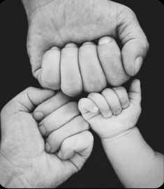 the hands of two adults holding a baby's hand in black and white photo