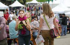 people walking around an outdoor market with tents in the background