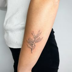 a woman's arm with a small flower tattoo on the left side of her arm