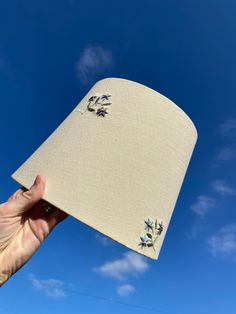 a hand holding up a white hat with blue sky in the background