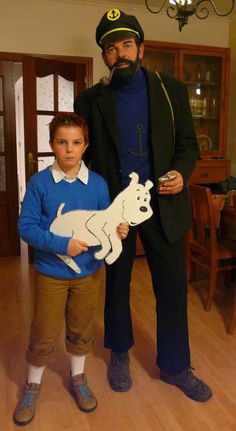 a man standing next to a young boy in a living room holding a cutout of a dog