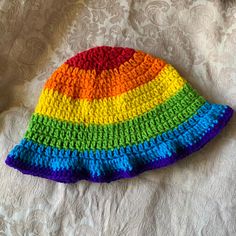 a multicolored crocheted hat laying on top of a bed