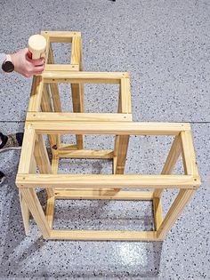 a person is holding a bottle near some wooden frames on the floor with their feet