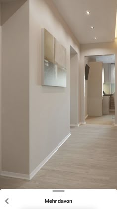 an empty hallway with white walls and wood floors