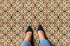 a person standing in front of a patterned floor with their feet propped up on the ground