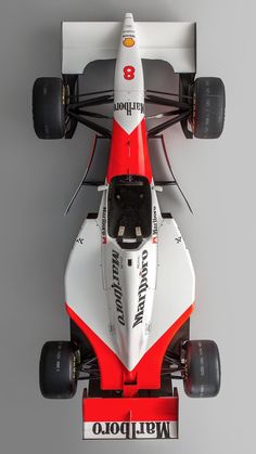 a white and red race car with black tires on the front, viewed from above