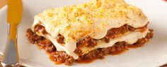 a piece of lasagna sitting on top of a white plate next to a fork