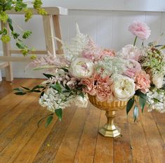 a gold vase filled with flowers on top of a wooden table