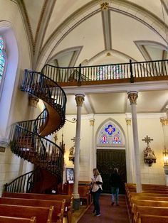 the inside of a church with two people standing in front of it and stairs leading up to the door