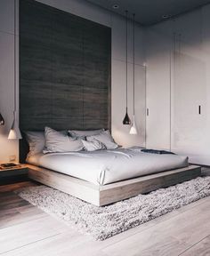 a large bed sitting on top of a wooden floor next to a wall mounted light