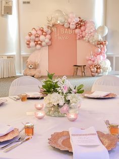 a table set up for a baby shower with pink and white balloons on the wall