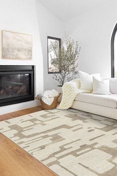 a living room with a large white rug and a fireplace in the corner next to it