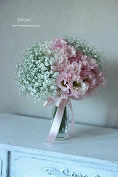 a bouquet of pink carnations and baby's breath in a glass vase