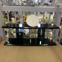 a glass shelf with a white plate sitting on top of it in the middle of a room