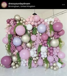 an arrangement of balloons and greenery is displayed on the wall in front of a white background