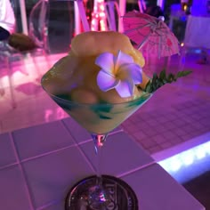 a cocktail with flowers and umbrellas on the table in a restaurant or bar setting