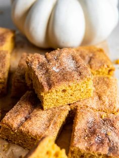 several pieces of cake sitting on top of a cutting board next to a white pumpkin