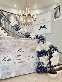 a large banner with balloons on it in front of a staircase and chandelier