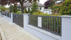 a fence is shown along the side of a sidewalk with trees and houses in the background