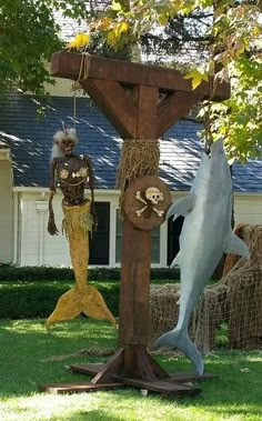 two statues of people and a dolphin in front of a house