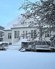 a large white house covered in snow next to a tree and steps leading up to the front door