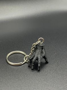 a keychain with a small black animal on it's side and a chain hanging from the end