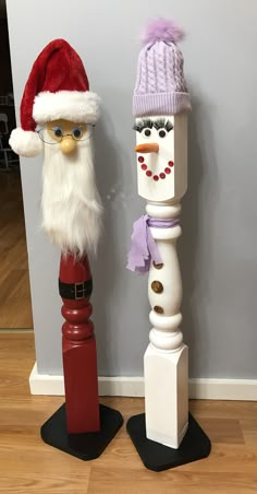 two snowmen standing next to each other in front of a wall with a santa hat on