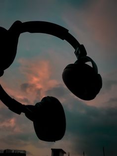 the silhouette of two boxing gloves hanging in front of a cloudy sky with clouds behind them